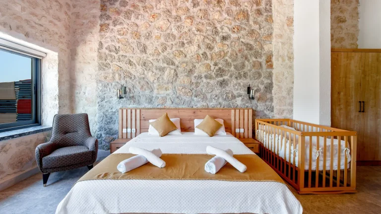 Chambre d'hôtel familiale avec lit double, lit bébé et mur en pierre