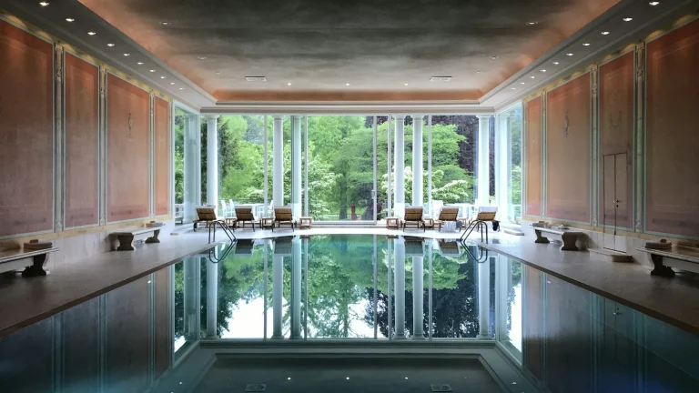 Piscine intérieure d'un hôtel avec reflets et vue sur la verdure