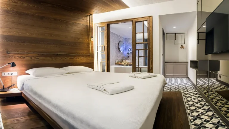 Chambre d'hôtel avec lit double, tête de lit en bois et salle de bain ouverte