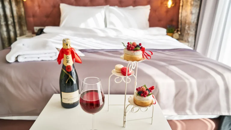Lit d'hôtel romantique orné d'une bouteille de champagne et de petits gâteaux
