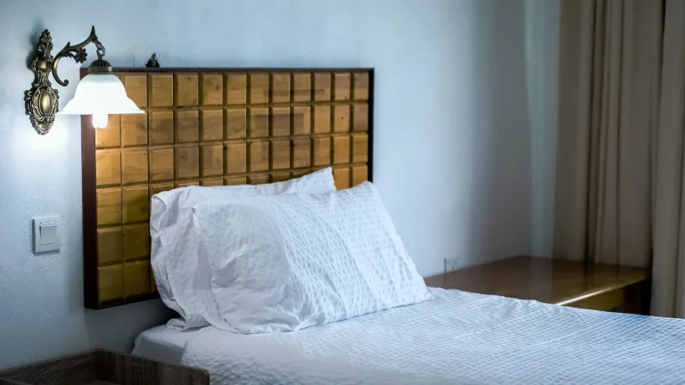 Chambre d'hôtel avec lit double, tête de lit dorée et lampe de chevet