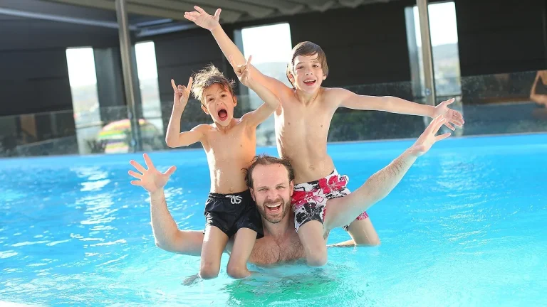 Un père et deux enfants jouent dans la piscine d'un hôtel
