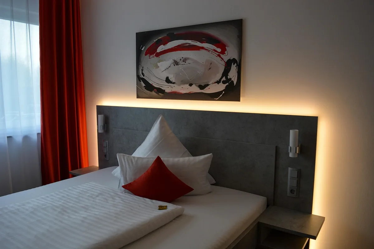 Chambre d'hôtel avec tête de lit éclairée et coussins rouges