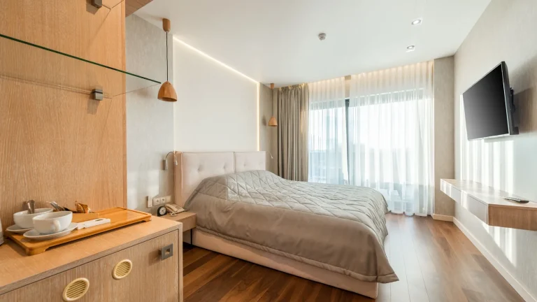 Chambre d'hôtel moderne en bois clair avec grande fenêtre