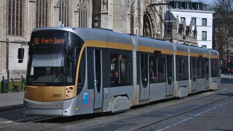 Un tramway STIB gris et jaune passe devant la cathédrale de Bruxelles